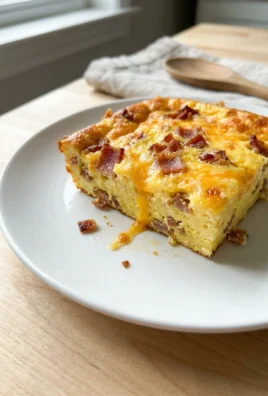 A serving of baked egg casserole showing bits of bacon and melted cheese.