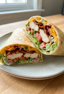 Two halves of a chicken bacon ranch wrap stacked, showing the layers inside.