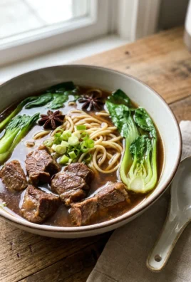 A close-up of a bowl of beef noodle soup with bok choy and noodles.
