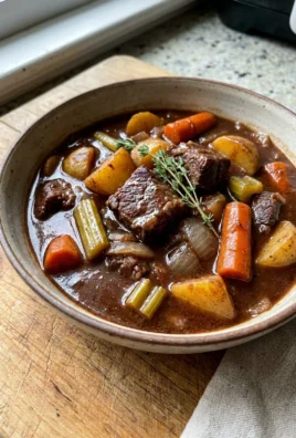 Beef browning in a red Dutch oven on a stovetop for stew.