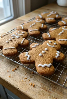 A stack of decorated gingerbread men cookies next to a glass of milk.